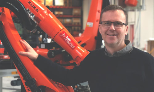 Billede af MIchael Friis med KUKA robotter i baggrunden.