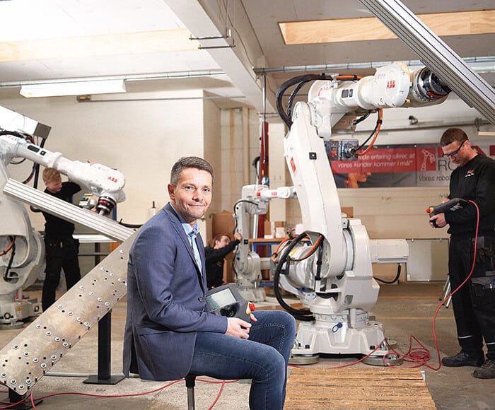 Direktor Kim Koertsen vor zwei ABB-Robotern